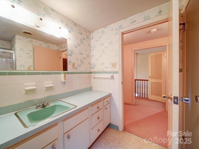 167 Cedar Ln, Troutman, NC 28166 - bathroom featuring wallpapered walls, vanity, wainscoting, a shower with door, and tile walls