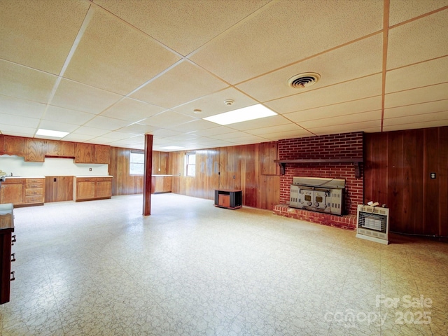 167 Cedar Ln, Troutman, NC 28166 - unfurnished living room with a paneled ceiling, tile patterned floors, wooden walls, a brick fireplace, and heating unit