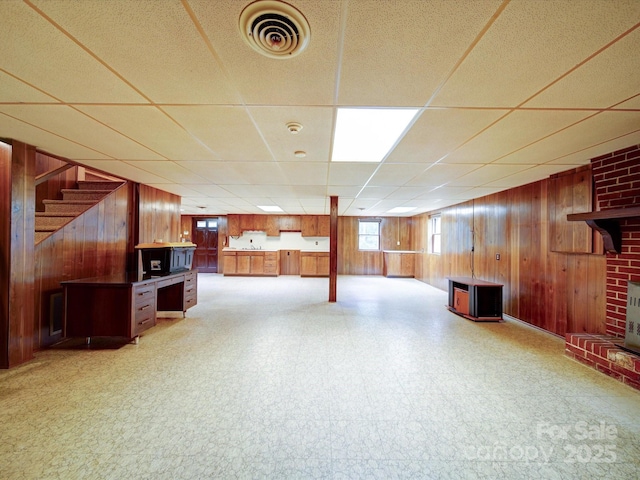 167 Cedar Ln, Troutman, NC 28166 - basement with wooden walls, a paneled ceiling, light floors, stairs, and a brick fireplace