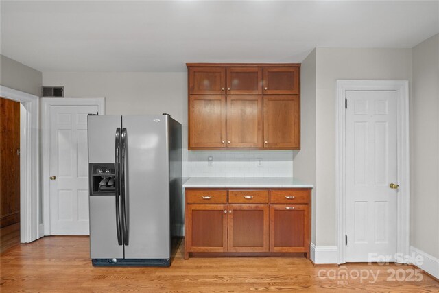 431 Sullivan Rd, Statesville, NC 28677 - kitchen with stainless steel fridge, light countertops, brown cabinetry, light wood-type flooring, and decorative backsplash
