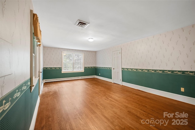 431 Sullivan Rd, Statesville, NC 28677 - spare room with a baseboard heating unit, wallpapered walls, wood finished floors, and baseboards