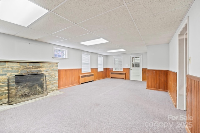 431 Sullivan Rd, Statesville, NC 28677 - below grade area featuring radiator, a wainscoted wall, a paneled ceiling, a stone fireplace, and plenty of natural light
