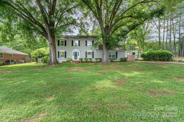 colonial home with a front yard and fence