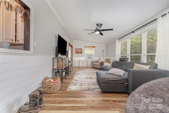 living room with ornamental molding, a ceiling fan, light wood-style floors, and vaulted ceiling