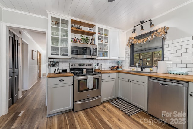 kitchen with stainless steel appliances, wooden counters, decorative backsplash, and a sink