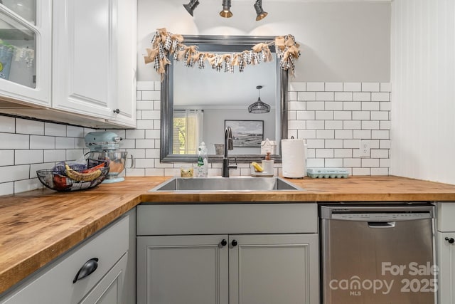 kitchen featuring wood counters, dishwasher, decorative backsplash, and a sink