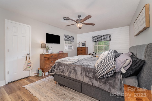 bedroom featuring cooling unit, a ceiling fan, wood finished floors, and baseboards