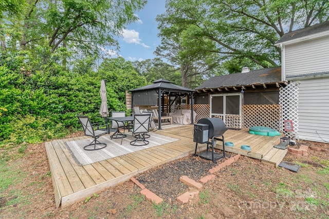 wooden terrace featuring outdoor dining space, area for grilling, and a gazebo