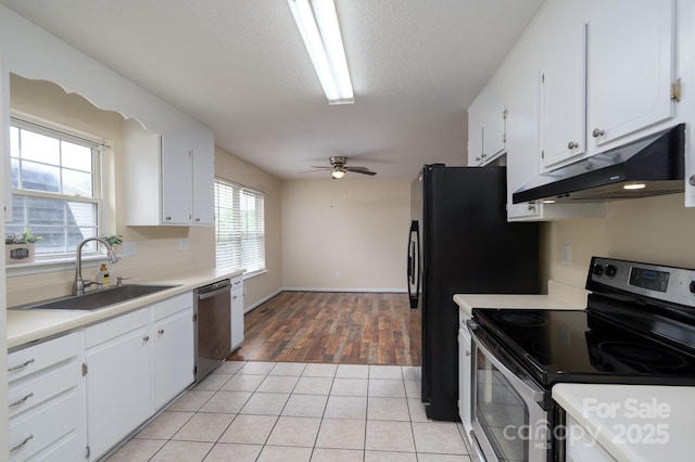 kitchen featuring appliances with stainless steel finishes, under cabinet range hood, a sink, and white cabinets