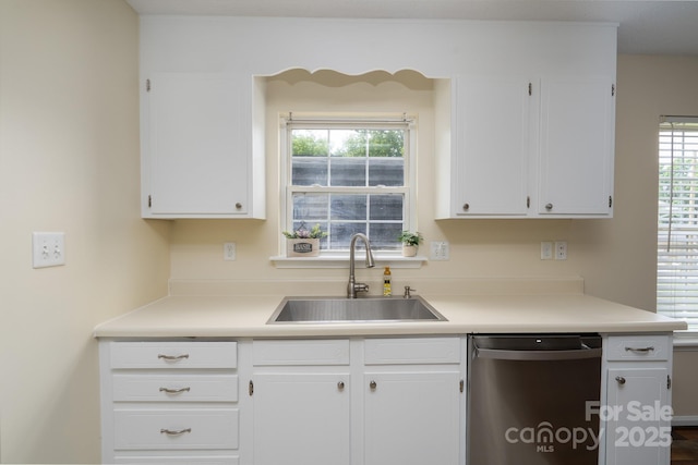 kitchen featuring stainless steel dishwasher, a sink, white cabinetry, and light countertops