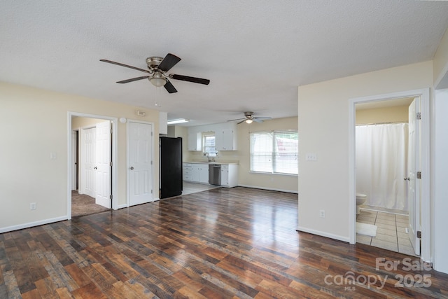 unfurnished living room with ceiling fan, dark wood-style flooring, baseboards, and a textured ceiling