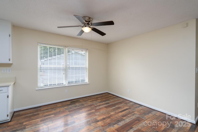 spare room featuring wood finished floors, a ceiling fan, and baseboards