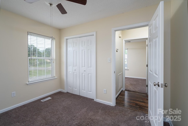 unfurnished bedroom with dark carpet, baseboards, a closet, and a textured ceiling