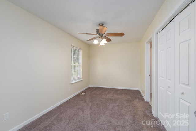 unfurnished bedroom featuring a closet, carpet floors, baseboards, and a ceiling fan