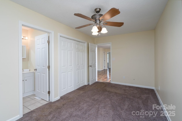 unfurnished bedroom featuring carpet floors, ensuite bath, a closet, and baseboards