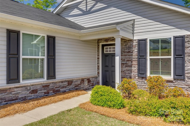 property entrance with stone siding and a shingled roof