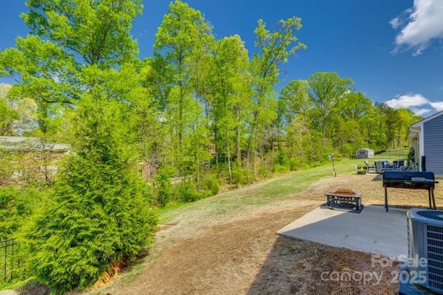 view of yard with an outdoor fire pit, a patio, and central AC