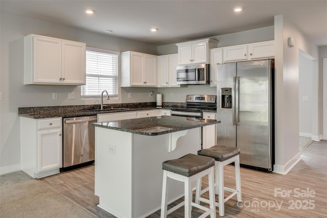 kitchen featuring a center island, a sink, light wood-type flooring, white cabinets, and appliances with stainless steel finishes