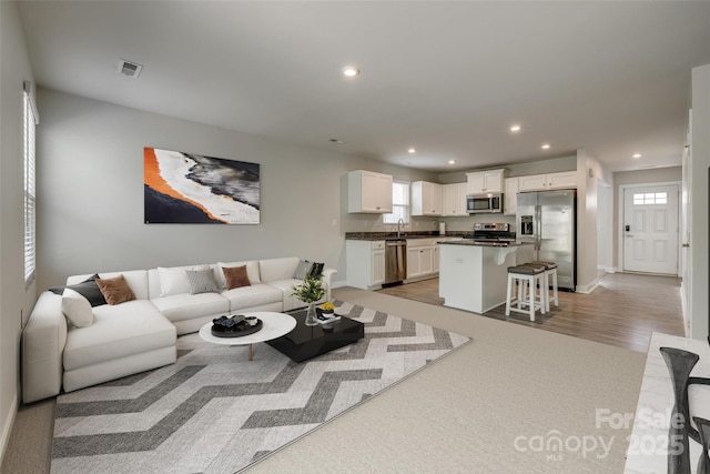 living area with baseboards, visible vents, recessed lighting, and light wood-style floors
