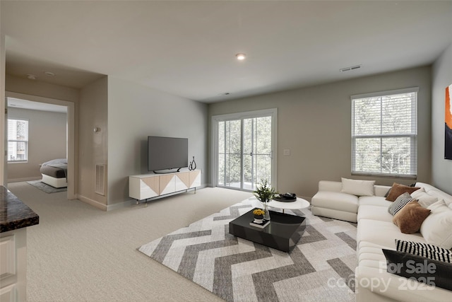 living area with recessed lighting, baseboards, visible vents, and light colored carpet