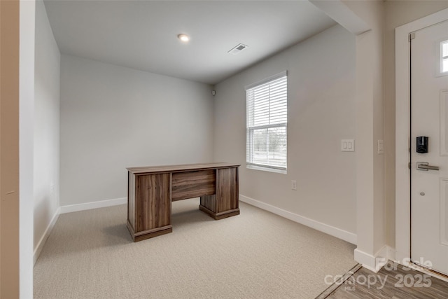 unfurnished office featuring plenty of natural light, baseboards, visible vents, and light colored carpet