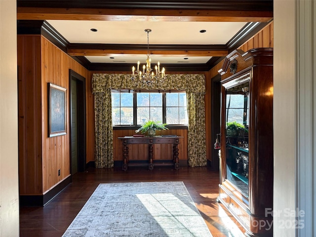 unfurnished dining area featuring a notable chandelier, beam ceiling, wooden walls, and wood finished floors