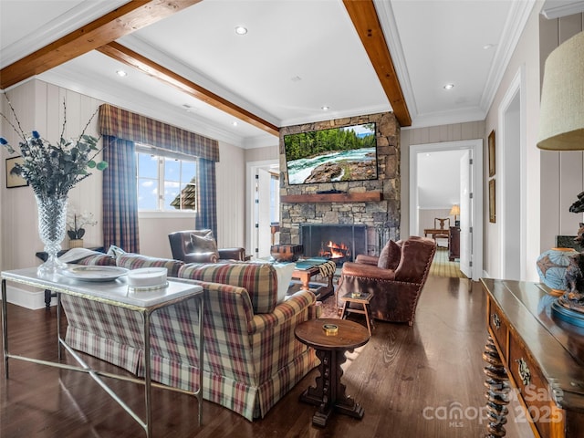living area featuring ornamental molding, wood finished floors, beamed ceiling, and a stone fireplace
