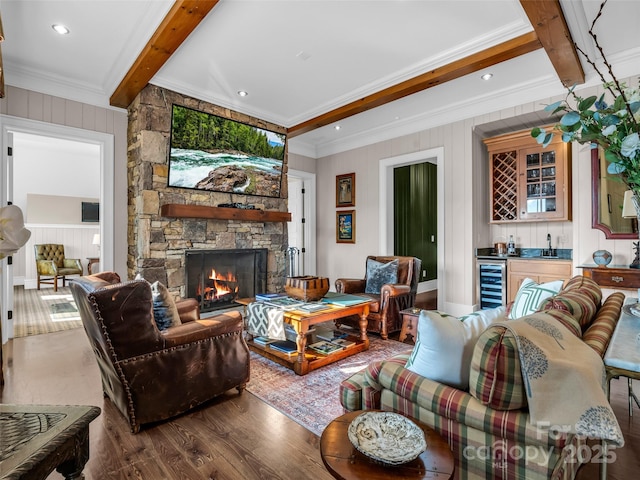living area featuring wet bar, a fireplace, wood finished floors, beverage cooler, and beamed ceiling