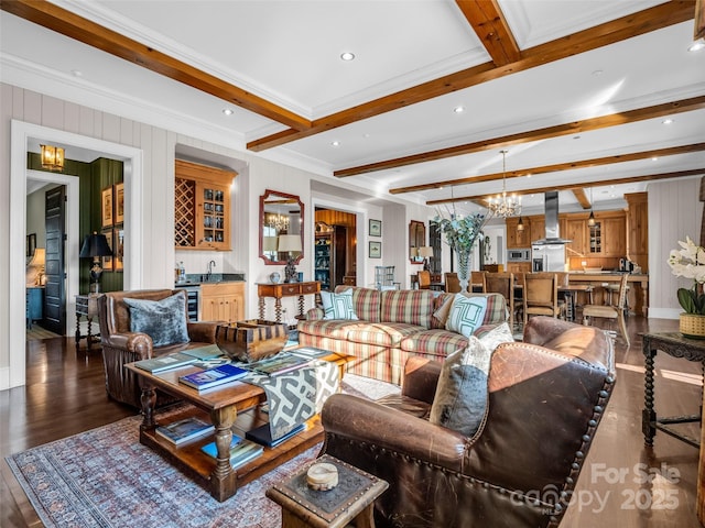 living area featuring wet bar, wood finished floors, beam ceiling, and an inviting chandelier