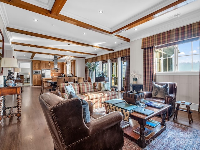living area with beam ceiling, wood finished floors, visible vents, ornamental molding, and an inviting chandelier
