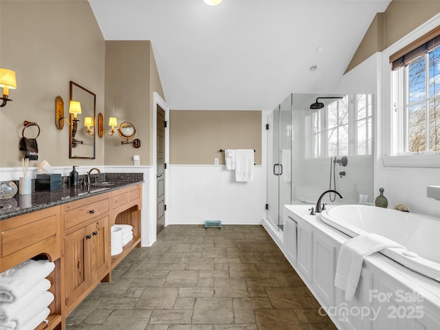 full bath featuring a wainscoted wall, a stall shower, lofted ceiling, and a bath