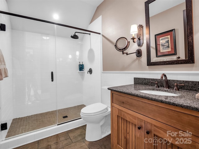 full bath featuring toilet, vanity, a stall shower, and tile walls