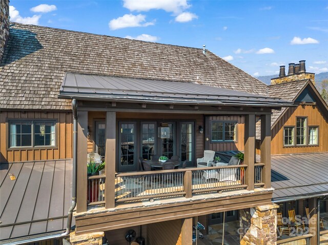 rear view of property featuring a chimney and board and batten siding