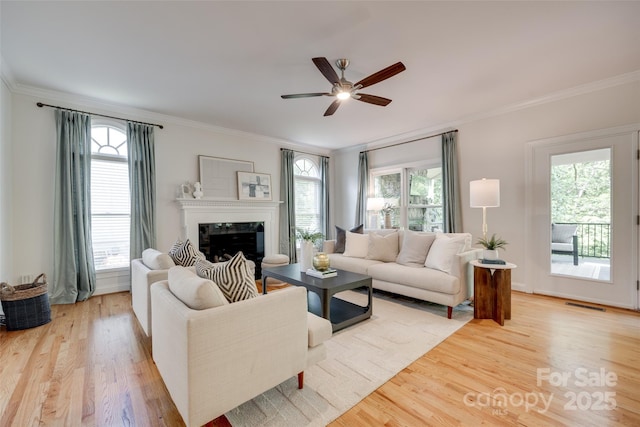 living room featuring light wood-style floors, ornamental molding, and plenty of natural light