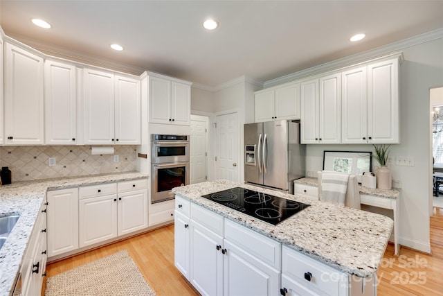 kitchen with white cabinets, crown molding, light wood-style floors, stainless steel appliances, and decorative backsplash