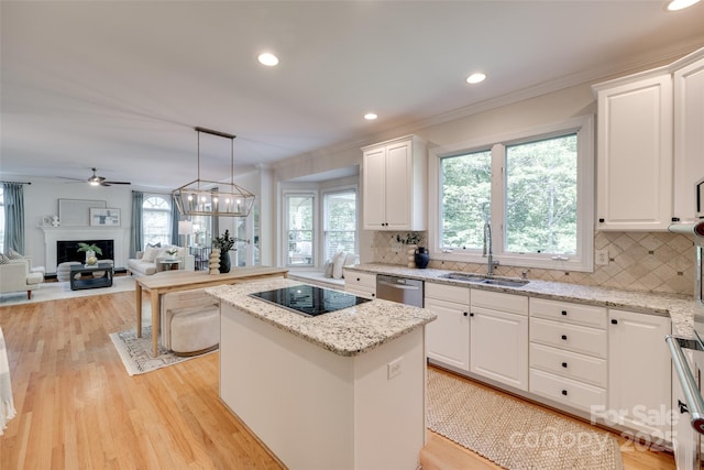 kitchen with a sink, black electric cooktop, a kitchen island, stainless steel dishwasher, and ornamental molding