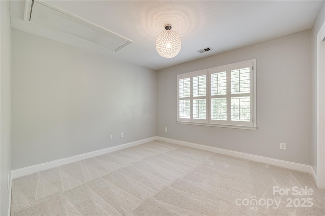 unfurnished room with visible vents, attic access, baseboards, and light colored carpet