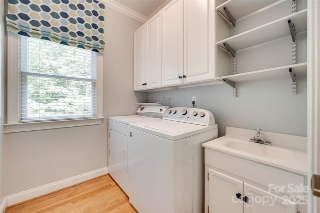 clothes washing area featuring crown molding, washer and dryer, light wood-style floors, a sink, and cabinet space