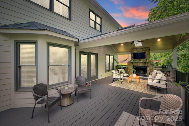 deck at dusk with an outdoor living space with a fireplace
