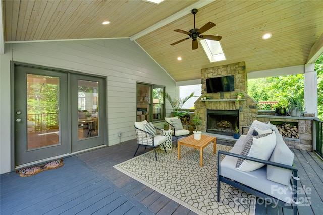 wooden deck featuring a ceiling fan and an outdoor living space with a fireplace