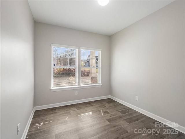 empty room featuring baseboards and dark wood-type flooring