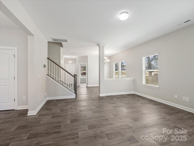 empty room featuring dark wood-style floors, visible vents, baseboards, and stairway