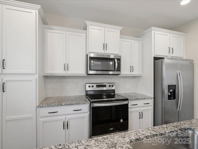 kitchen with white cabinetry, light stone counters, tasteful backsplash, and appliances with stainless steel finishes
