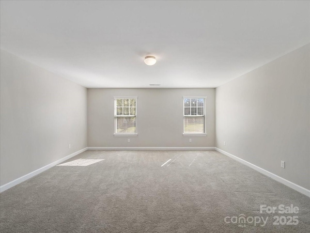 unfurnished room featuring light carpet, baseboards, and a wealth of natural light