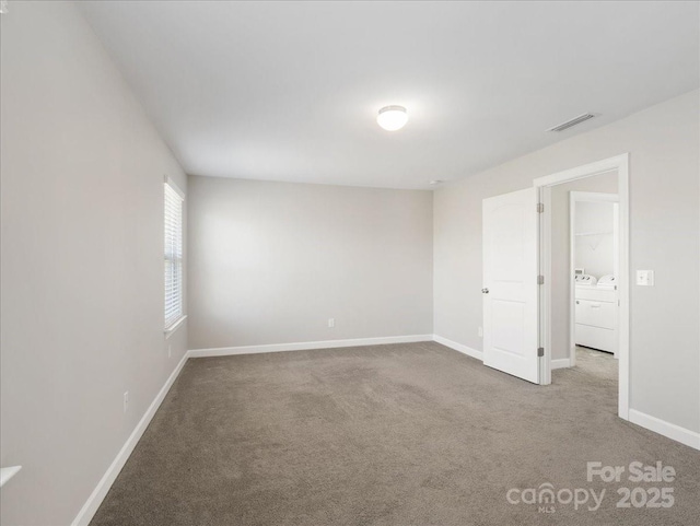 carpeted spare room with baseboards, visible vents, and washing machine and clothes dryer