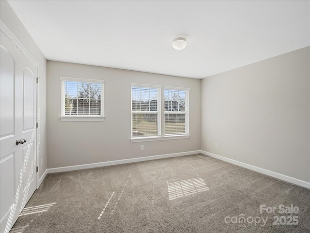 unfurnished room with a wealth of natural light, baseboards, and carpet flooring