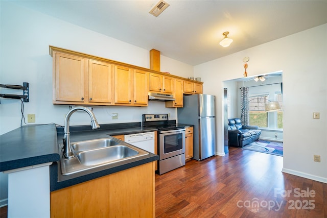 kitchen featuring a sink, appliances with stainless steel finishes, dark countertops, under cabinet range hood, and visible vents