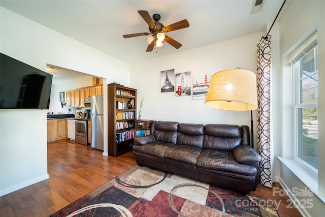 living room with baseboards, dark wood-style floors, visible vents, and a ceiling fan
