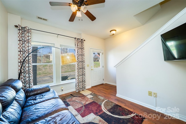 living area featuring baseboards, ceiling fan, visible vents, and wood finished floors