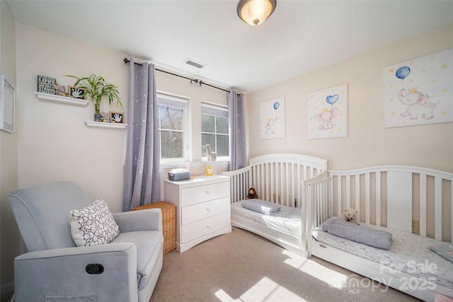 carpeted bedroom featuring visible vents and a nursery area